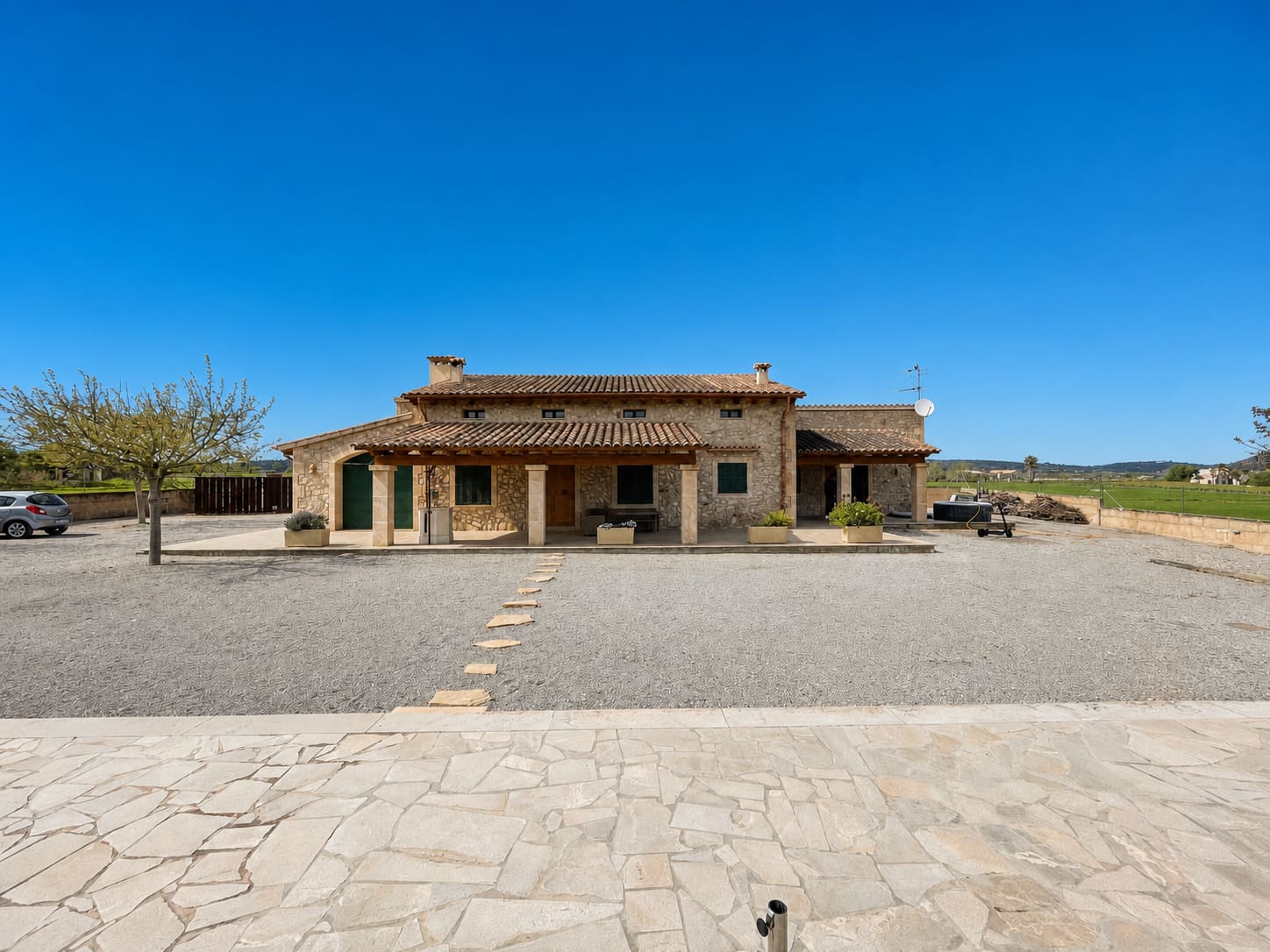 Mallorquinische Finca mit großem Vorplatz und wolkenfreiem blauem Himmel
